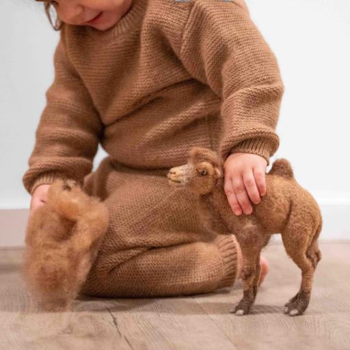 Babykleidung und Kinderkleidung  Kind in brauner Kleidung spielt mit Kamel